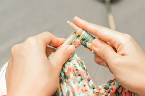 a woman is knitting a piece of fabric